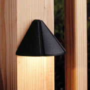 Textured black deck light with triangular hood, mounted on wood deck