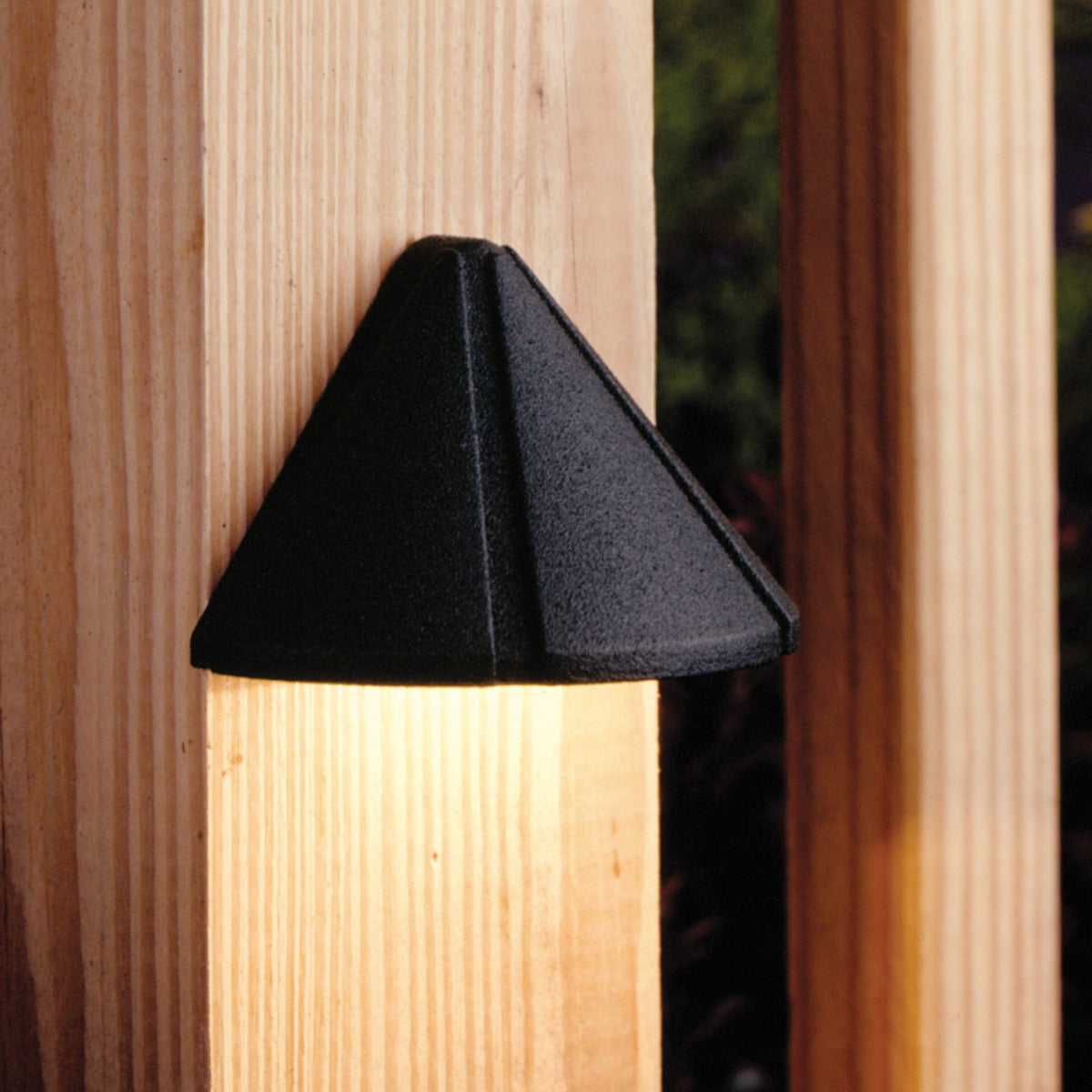 Textured black deck light with triangular hood, mounted on wood deck