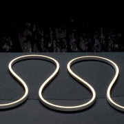 LED neon strip with cool white U-shaped glow, close-up on black surface