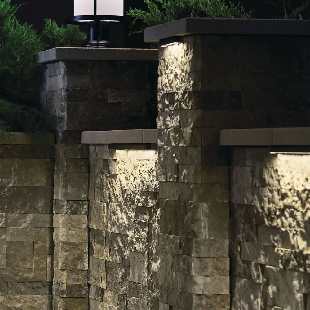 Warm-lit LED hardscape light mounted on stone wall, rectangular light bar