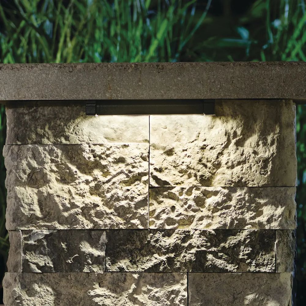 Warm LED hardscape lights on stone wall with black rectangular light bars
