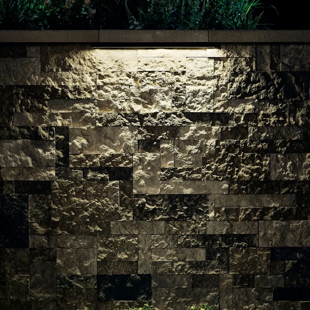 LED hardscape light illuminating a stone wall with warm light