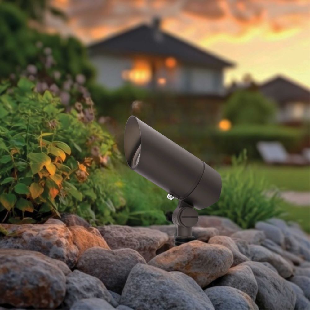 Bronze landscape LED accent light mounted on ground rocks with angled cylindrical housing