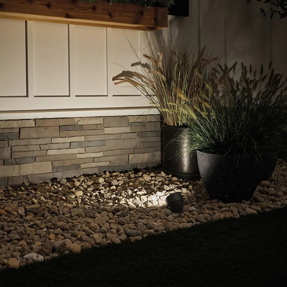 Architectural bronze LED landscape accent light installed beside a rock bed
