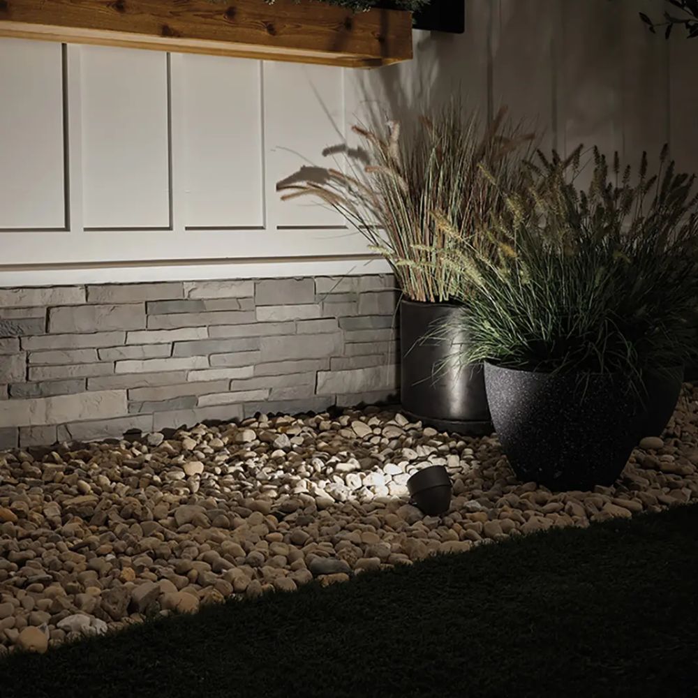 Architectural bronze LED landscape accent light lighting a stone landscaping area