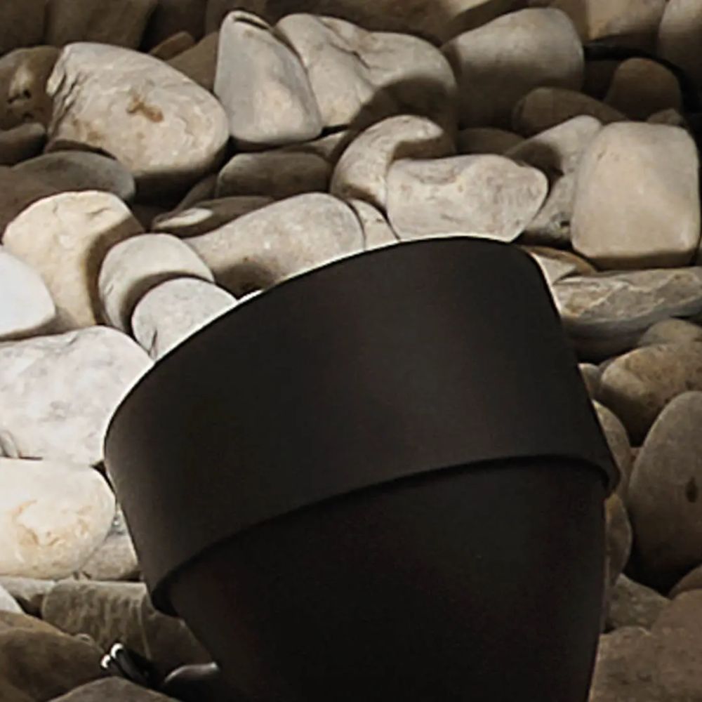 Kichler textured black LED landscape accent flood light resting on rocks with rounded cap