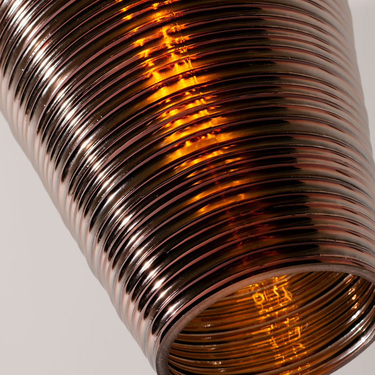 Close-up of ribbed amber glass pendant shade with visible glowing bulb