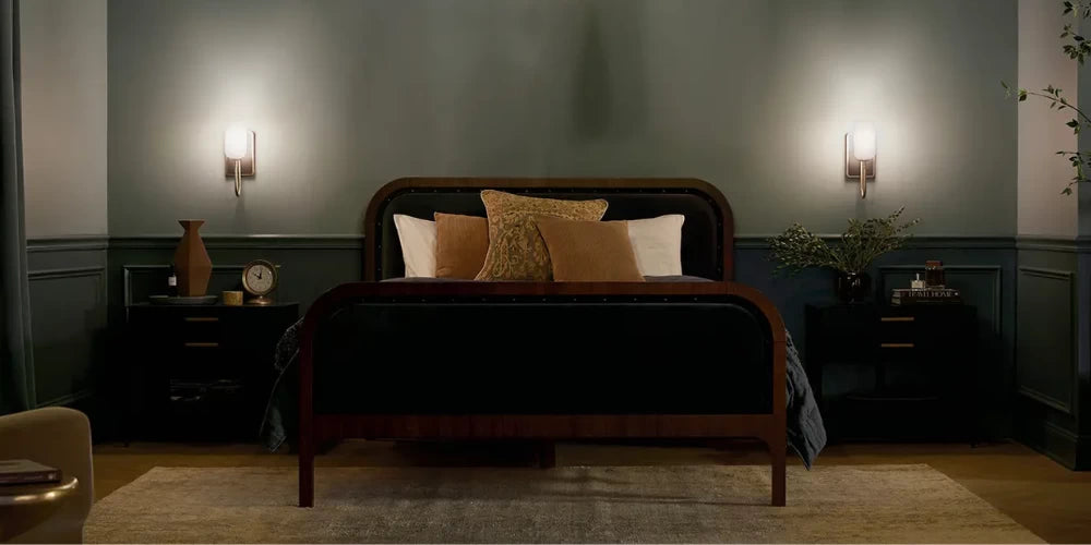 Hardwired bedside wall sconce with concealed junction box and no visible cord mounted symmetrically beside bed headboard