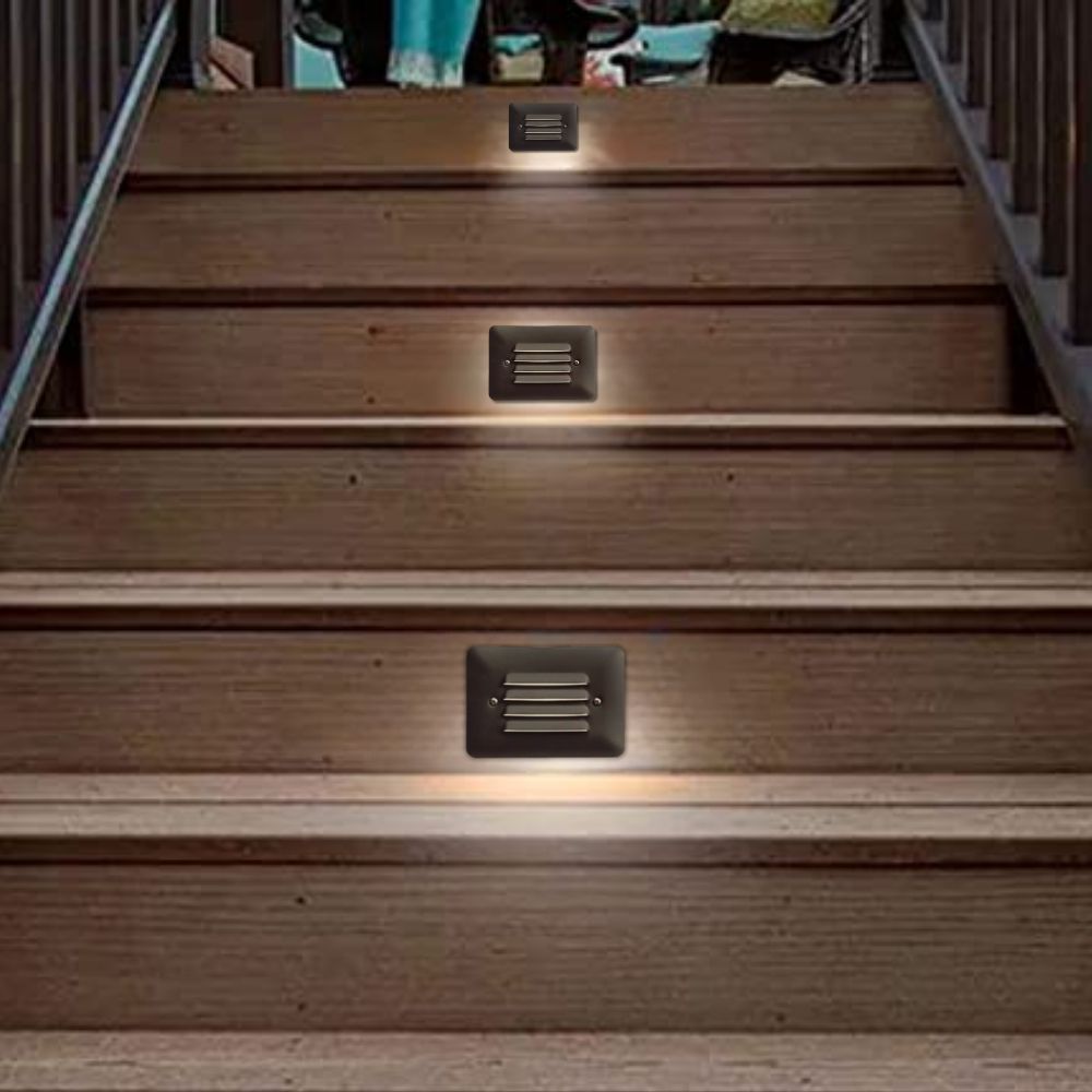 Square black step LED lights with vented grilles installed in wooden stair tread