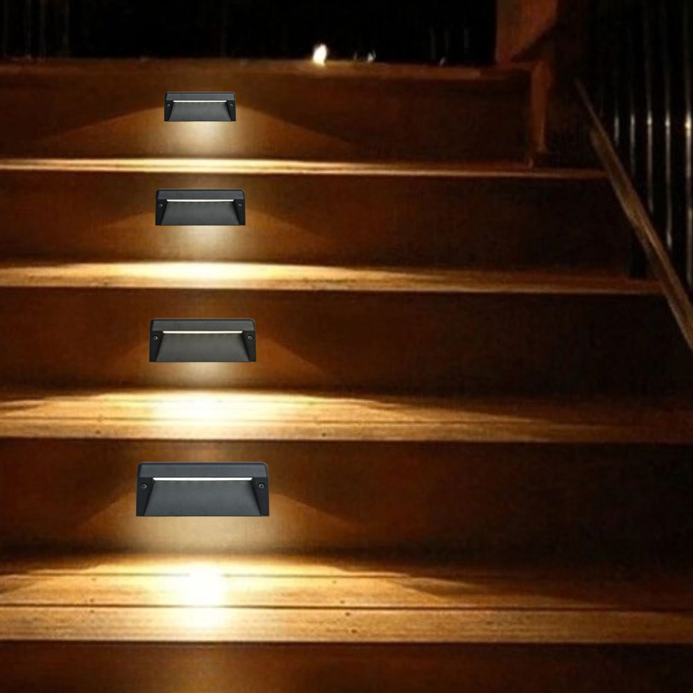 Set of textured black LED step lights on indoor stairs emitting warm light