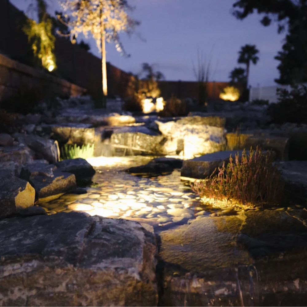 LED landscape lights illuminating a rocky garden path and water feature at dusk