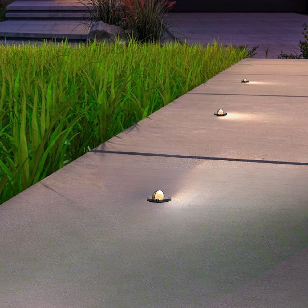 Outdoor deck and path LED well lights with small brass half-moon fixtures emitting light