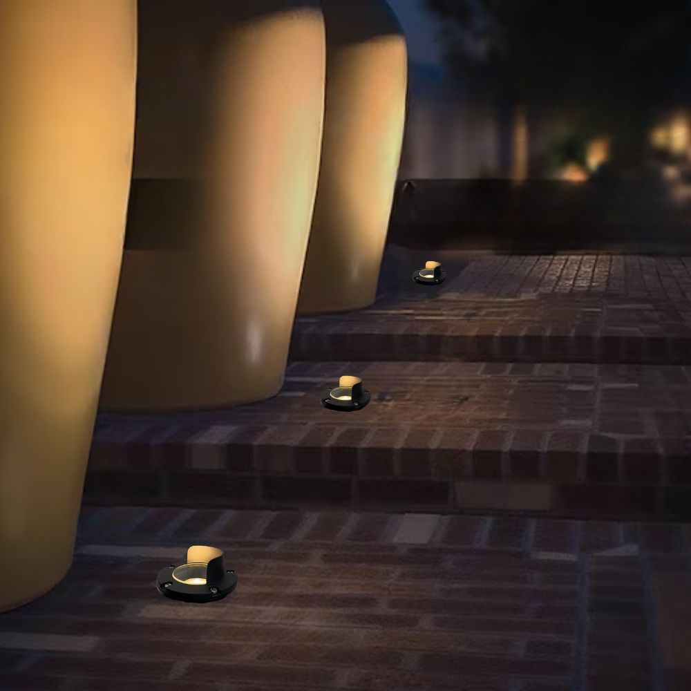 Outdoor step well lights with brass shields and warm glow along the walkway