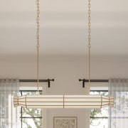 Linear 6-light chandelier with brass frame and white ribbed glass tube shade, suspended by chains.