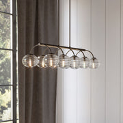 Dark bronze linear chandelier with clear ribbed glass globes on an arched bar frame