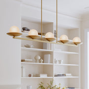 Legacy brass linear chandelier with five amber swirl glass globe shades