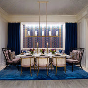 Satin brass 5-light island pendant hanging above dining table with five glowing bulbs